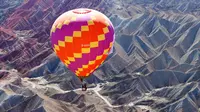 Sebuah balon udara terbang di langit Taman Geologi Nasional Danxia di Zhangye, Provinsi Gansu, China barat laut, pada 26 Juli 2020. Sebuah festival balon udara internasional dibuka di Zhangye pada Minggu (26/7). Total 100 balon udara akan ditampilkan dalam festival tersebut. (Xinhua/Cheng Lin)