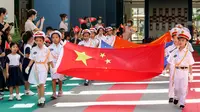 Anak-anak memegang bendera China saat upacara pengibaran bendera di sebuah taman kanak-kanak di Shenzhen, Provinsi Guangdong, China, Selasa (30/6/2020). Hong Kong menandai 23 tahun penyerahan dari Inggris ke Cina pada 1 Juli. (STR/AFP)