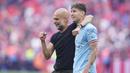 Ekspresi bahagia Pep Guardiola (kiri) dan John Stones setelah berhasil membawa Manchester City keluar sebagai juara Piala FA 2022/2023 dalam pertandingan final FA Cup melawan Manchester United yang berlangsung di Wembley, Sabtu (3/6/2023) WIB. (AP Photo/Dave Thompson)