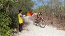 Seorang anggota Pramuka menjadi Marshall saat pebalap mengikuti Mountain Bike Cross Country Marathon pada Festival Pesona Tanjung Lesung 2017 di Tanjung Lesung, Banten (23/9/2017). MTB XCM tersebut menempuh jarak 48 km. (Bola.com/Nicklas Hanoatubun)