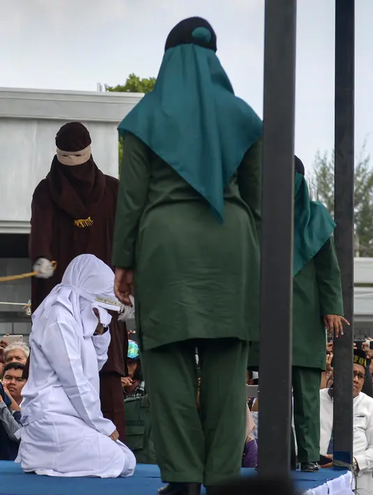 Petugas syariah mencambuk pekerja seks komersial (PSK) online di halaman Masjid Jamik Lueng Bata, Banda Aceh, Aceh, Jumat (20/4). Hukum cambuk di ruangan terbuka ini bisa jadi menjadi yang terakhir. (CHAIDEER MAHYUDDIN / AFP)