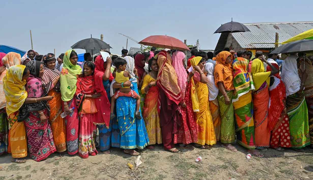 Para pemilih berdiri dalam antrean untuk memberikan suara mereka saat pemungutan suara tahap kedua untuk pemilihan umum India di desa Gashbari di distrik Darrang, negara bagian Assam pada tanggal 26 April 2024. (Biju BORO/AFP)