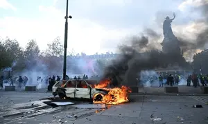Sebuah mobil terbakar di Place de la Republique, Paris, Prancis, saat berlangsungnya demonstrasi memprotes kenaikan biaya hidup pada Sabtu (17/10/2026). (Dok. AP Photo/Emma Da Silva)