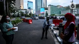 Suasana pembagian takjil kepada pejalan kaki di Kawasan Bundaran HI, Jakarta, Selasa (20/4/2021). Kegiatan berbagi takjil yang digagas oleh Pewarta Foto Indonesia Jakarta (PFIJ) ini dilaksanakan setiap hSelasa dan Jumat selama bulan Ramadhan sebagai bentuk solidaritas. (Liputan6.com/JohanTallo)