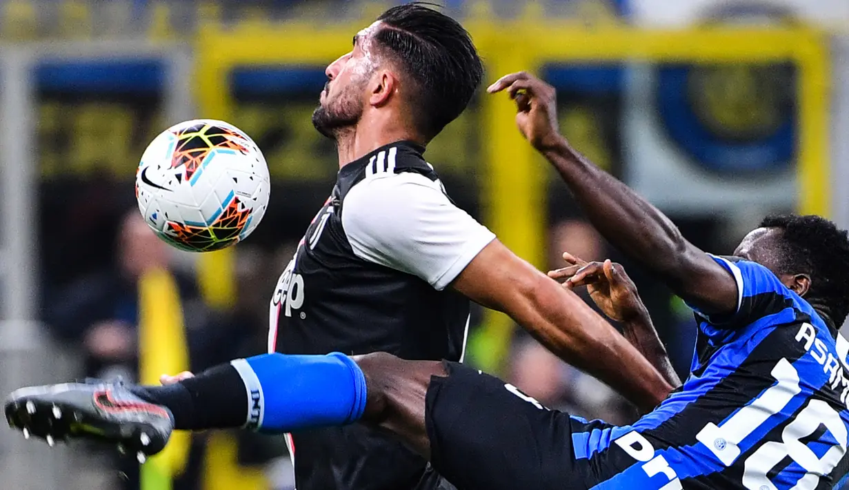 Pemain bertahan Inter Milan, Kwadwo Asamoah berebut bola dengan pemain Juventus, Emre Can dalam lanjutan kompetisi Serie A 2019-2020 di Stadion Giuseppe Meazza, Minggu (6/10/2019). Juventus memenangi duel bertajuk Derby d'Italia dengan keunggulan 2-1 atas Inter. (Alberto PIZZOLI / AFP)