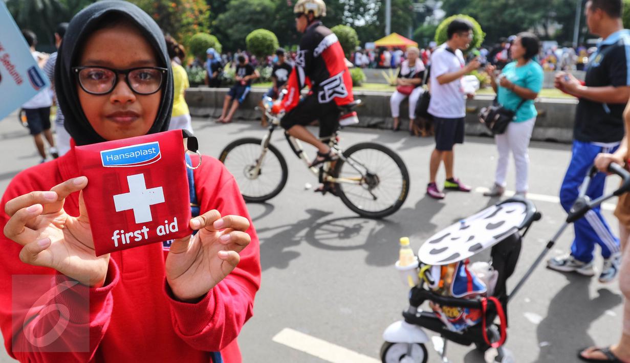 Relawan menunjukkan mini kit P3K yang akan dibagikan kepada pengguna CFD di Jalan MH Thamrin, Jakarta, Minggu (25/9). Kegiatan ini mengajak masyarakat untuk selalu siap dengan P3K. (Liputan6.com/Fery Pradolo)