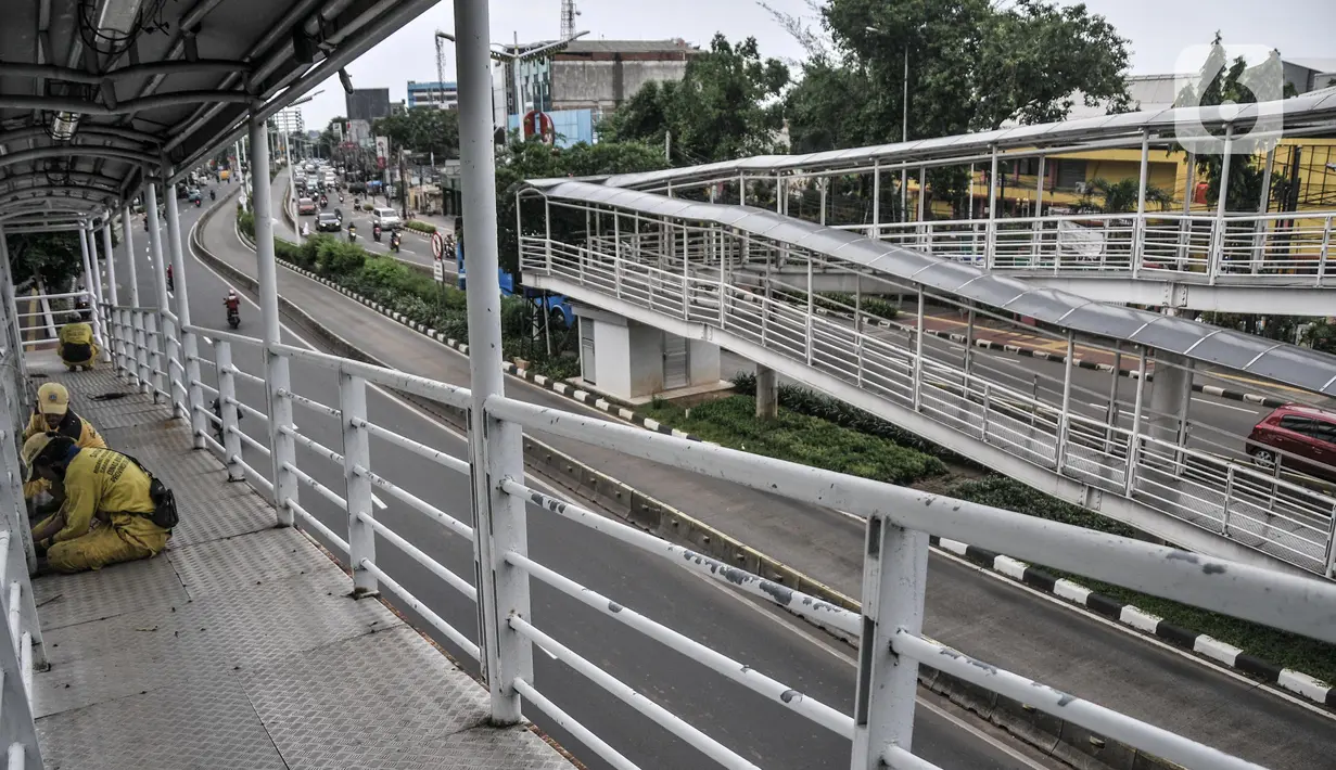Petugas Sudin Bina Marga Jakarta Timur memperbaiki jembatan penyeberangan orang (JPO) di Jalan Otto Iskandardinata (Otista), Jatinegara, Rabu (9/2/2022). Perbaikan JPO itu tindak lanjut pasca insiden tertimpa pohon tumbang pada November tahun lalu akibat cuaca ekstrem. (merdeka.com/Iqbal S Nugroho)