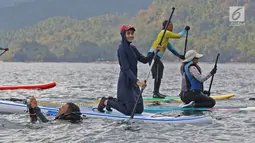 Istri bupati Trenggalek Mochammad Nur Arifin, Novita Hardini tersenyum saat olah raga Stand Up Paddle di Pantai Mutiara, Trenggalek, Jawa Timur, Sabtu (7/9/2019). Bermain Stand Up Paddle merupakan salah satu olah raga air atau wisata. (Liputan6.com/Herman Zakharia)