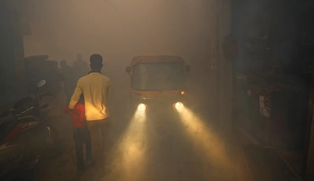 Komuter berjalan melewati asap dari fogging di daerah padat penduduk di New Delhi, India, Rabu (27/10/2021). New Delhi telah melaporkan ratusan kasus demam berdarah, dengan lebih dari 200 kasus baru dalam seminggu terakhir, menurut laporan yang dirilis pada hari Senin. (AP Photo/Manish Swarup)