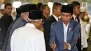 Presiden Joko Widodo atau Jokowi menyalami jemaah salat id saat tiba di Masjid Istiqlal, Jakarta, Rabu (5/6/2019). Jokowi mengenakan setelan jas abu-abu, kemeja putih serta peci hitam. (Liputan6.com/JohanTallo)