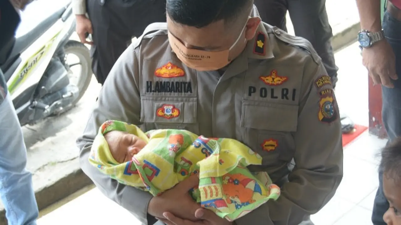 Kapolsek Tampan Kompol Hotmartua Ambarita menggendong bayi yang dibuang orangtuanya di salah satu panti asuhan di Pekanbaru.