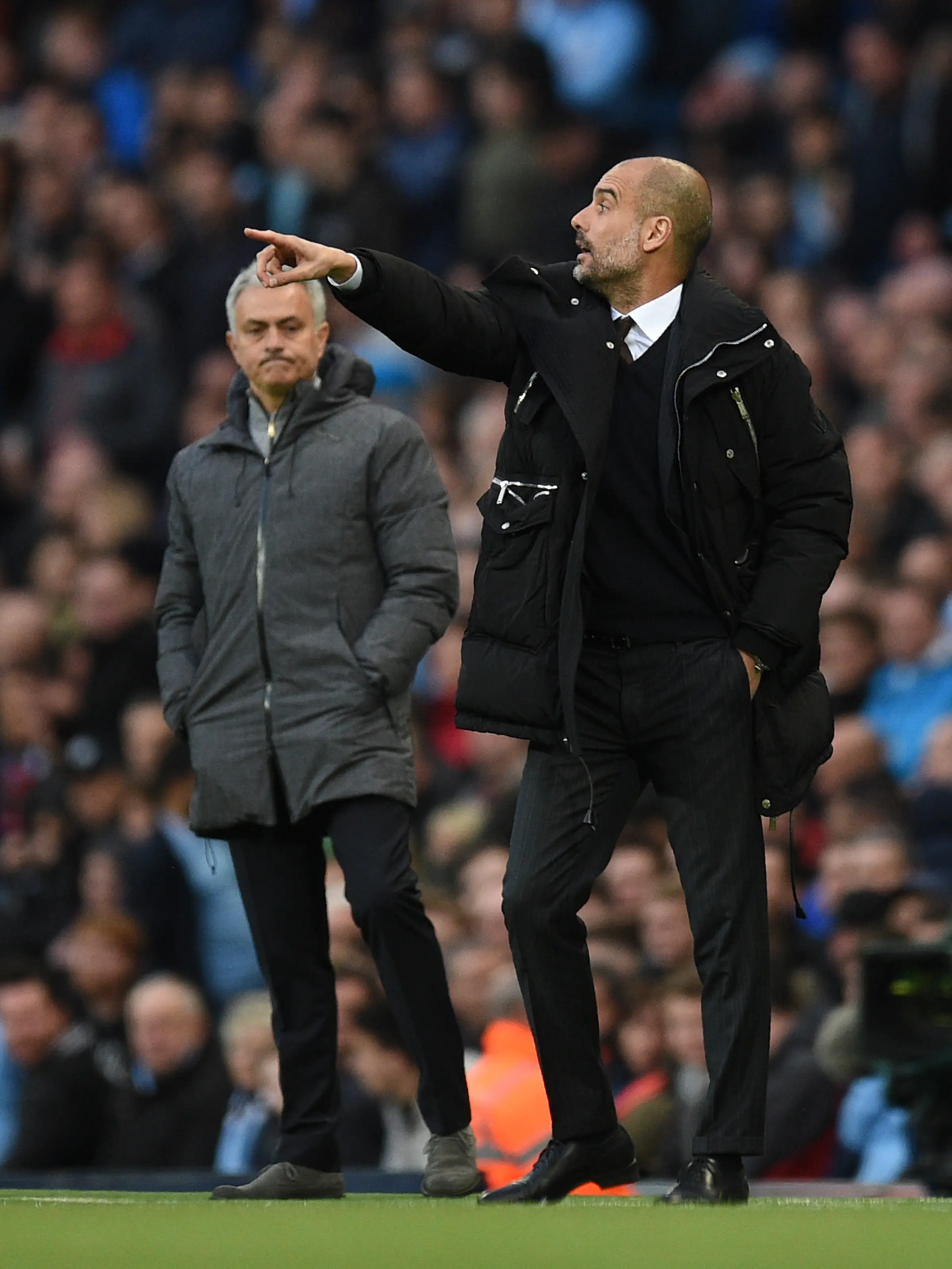 Pelatih Manchester City, Josep Guardiola mengintruksikan para pemainnya di samping Jose Mourinho selama pertandingan Liga Inggris di stadion Etihad, Inggris, (27/4). MU berada di peringkat ke lima dan City di peringkat empat. (AFP Photo/Oli Scarff)