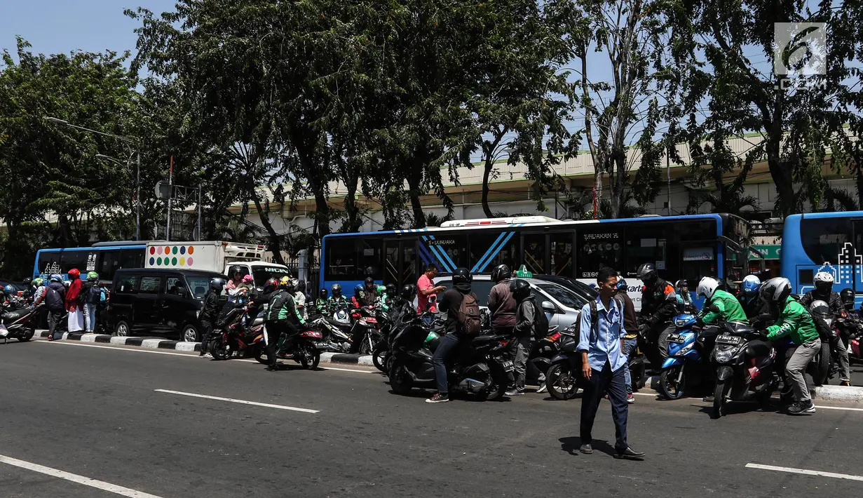 Pengendara berusaha pindah jalur dengan mengangkat sepeda motor mereka melewati pembatas jalan di kawasan Ridwan Rais, Jakarta, Rabu (21/8/2019). Pengendara motor tersebut berpindah jalur disebabkan tidak sabar menunggu kemacetan. (Liputan6.com/Johan Tallo)