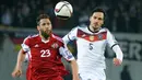 Penyerang Georgia, Levan Mchedlidze (kiri) berebut bola dengan bek Jerman Mats Hummels saat kualifikasi Piala Eropa 2016 di Locomotiv Stadium, Minggu (29/3/2015). Jerman menang 2-0 atas Georgia. (AFP PHOTO/Vano Shlamov)