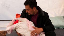 Khalil al-Suwadi menggendong keponakannya Afraa, bayi Suriah yang lahir di bawah reruntuhan setelah gempa bumi 6 Februari yang melanda Turki dan Suriah, di kota Jindayris yang dikuasai pemberontak di Suriah utara, Selasa (21/2/2023). Afraa ditemukan di bawah reruntuhan bangunan dengan tali pusar masih terikat dengan ibunya yang sudah meninggal bersama dengan ayahnya dan keempat saudara kandungnya. (Rami al SAYED / AFP)