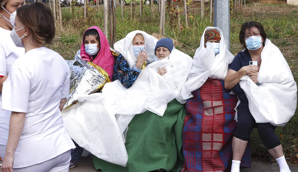 Pasien duduk setelah kebakaran di bagian ICU COVID-19 Rumah Sakit Penyakit Menular di pelabuhan Laut Hitam Constanta, Rumania (1/10/2021). Pihak berwenang mengatakan kebakaran telah menewaskan sembilan pasien COVID-19 di ICU. (AP Photo/Costin Dinca)
