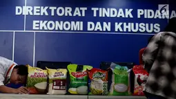 Petugas menata beras yang ditampilkan saat jumpa pers di Gedung Bareskrim, Jakarta, Jumat (25/8). Bareskrim menjelaskan temuan baru soal tindak pidana penipuan terkait kualitas beras yang tidak sesuai kemasan. (Liputan6.com/Johan Tallo)