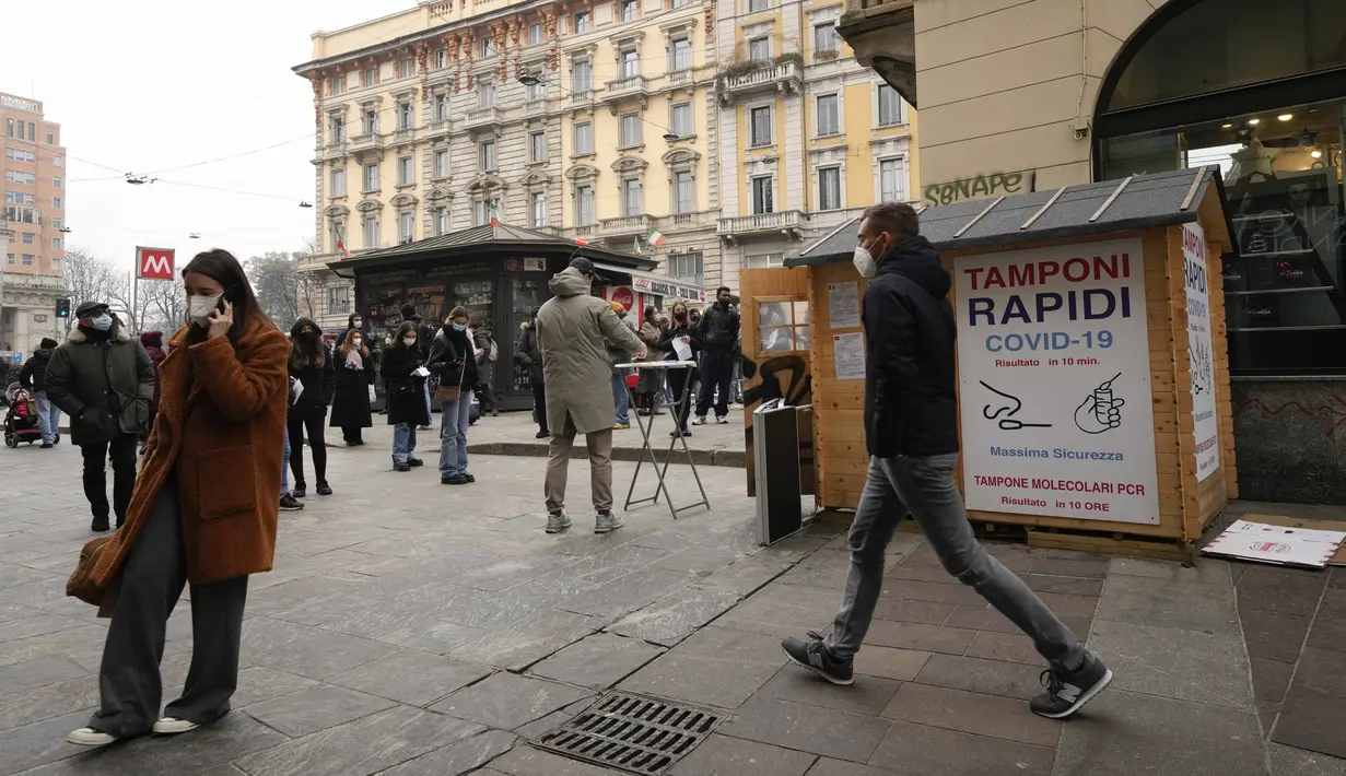 Orang-orang berbaris di situs pengujian COVID-19 mobile di sebelah apotek di Milan, Italia, Selasa (21/12/2021). Negara-negara di seluruh Eropa mempertimbangkan pembatasan yang lebih ketat guna membendung gelombang baru infeksi COVID-19 yang didorong oleh varian omicron. (AP Photo/Luca Bruno)