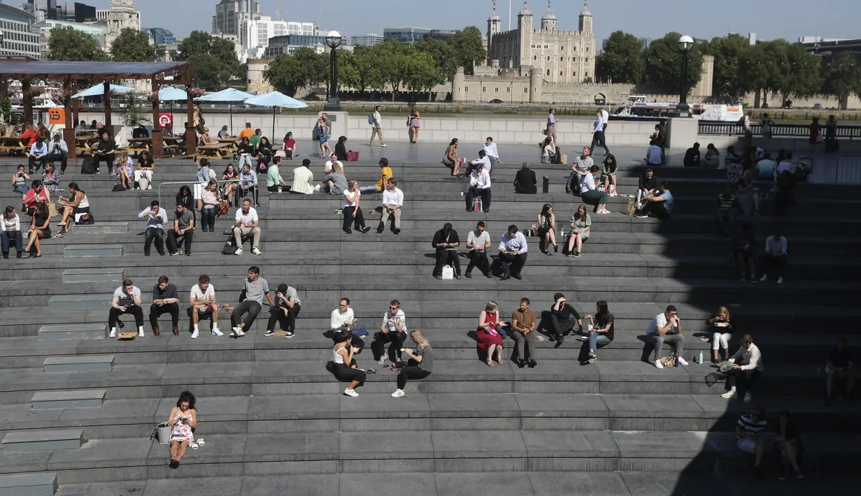 Orang-orang makan siang sambil duduk di bawah sinar matahari di Scoop dengan latar belakang Menara London saat suhu mendekati 30 derajat celsius di London, Selasa (7/9/2021).  (AP Photo/Tony Hicks)