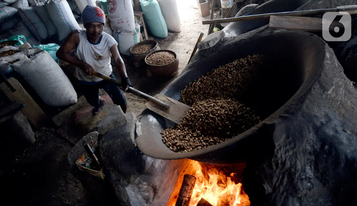 Pekerja mengolah kacang dengan media pasir di salah satu industri rumahan pembuatan kacang sangrai di Kawasan Keranggan, Tangerang Selatan, Selasa (11/8/2020). Kacang sangrai yang dipasarkan seharga Rp10.000 per kg itu mulai mengalami kenaikan pesanan dibanding bulan lalu. (merdeka.com/Dwi Narwoko)