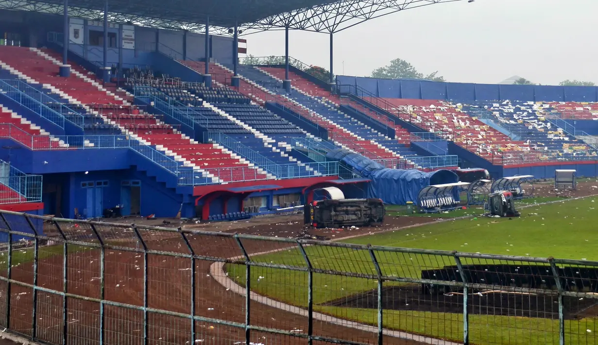 Kendaraan polisi yang terbalik terlihat di lapangan setelah tragedi kerusuhan pada pertandingan sepak bola antara Arema Vs Persebaya di Malang, Jawa Timur, Minggu (2/10/2022). Dari 129 orang yang meninggal dunia dalam kejadian tersebut, dua orang merupakan polisi. (AP Photo/Hendra Permana)