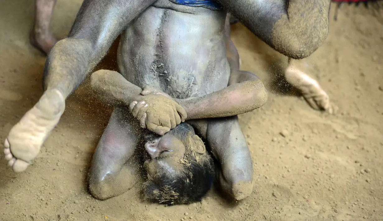 Pemuda India mengunci lawannya dalam pertandingan gulat tradisional di Allahabad, India pada Senin (5/8/2019). Pertandingan yang berlangsung di klub gulat Loknath Vyayamsala untuk menandai Festival Nag Panchami. (SANJAY KANOJIA / AFP)