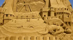 Orang-orang berpose dengan patung pasir tertinggi di dunia, yang sedang dibangun di Blokhus, Denmark, Rabu (7//2021). Perancangnya, Wilfred Stijger mengatakan pandemi corona covid-19 telah menjadi inspirasi pembuatan istana pasir tersebut.  (Claus Bjoern Larsen/Ritzau Scanpix/AFP)