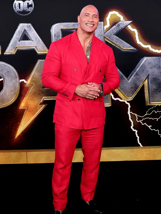 Aktor AS Dwayne Johnson tiba untuk pemutaran perdana film 'Black Adam' di Time Square, New York City, Amerika Serikat, 12 Oktober 2022. Dwayne Johnson yang sering dipanggil dengan julukan The Rock bertelanjang dada di balik jas merahnya. (Jamie McCarthy/Getty Images/AFP)