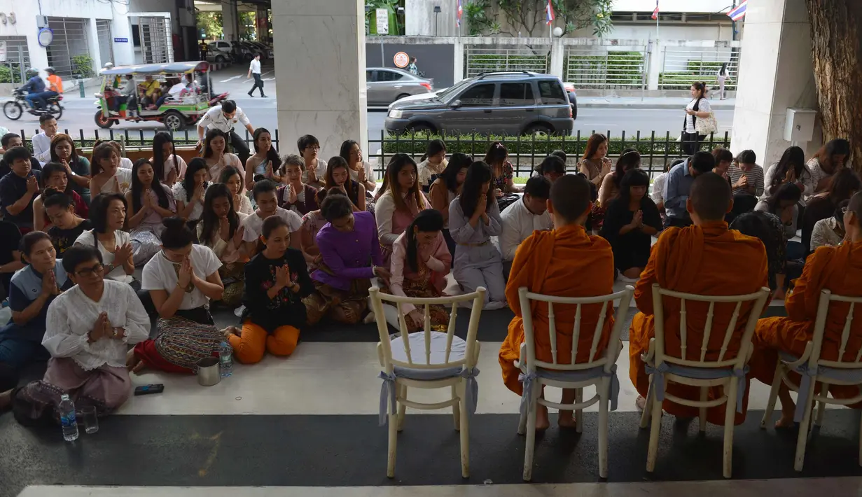 Sejumlah wanita mengenakan kostum tradisional mempersembahkan doa mereka di hadapan para biksu Buddha selama upacara keagamaan sebagai persiapan untuk festival tahun baru Songkran di Bangkok, Thailand (9/4). (AFP Photo/Romeo Gacad)