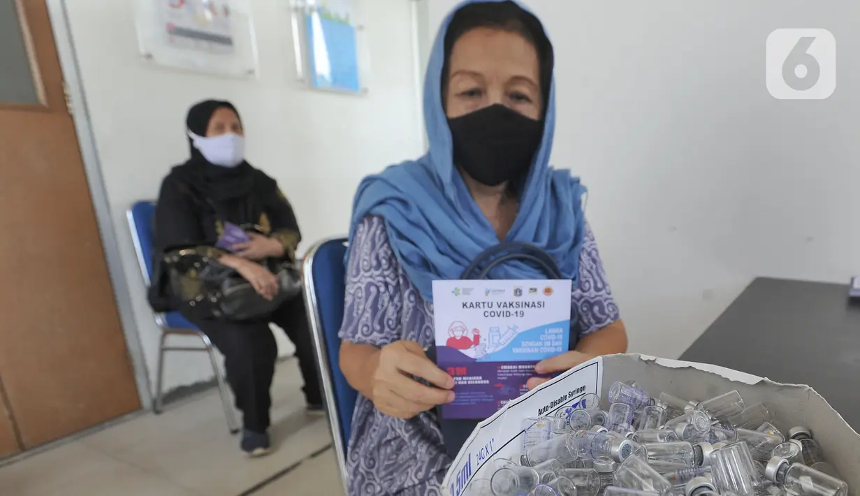 Tenaga kesehatan berusia lanjut menunjukan kartu vaksin di Puskesmas Kecamatan Jagakarsa, Jakarta Selatan, Kamis (11/2/2021). Sekitar 11 ribu nakes lansia yang berusia di atas 60 tahun saat ini menjadi prioritas penerima vaksin untuk mengurangi resiko atas infeksi covid-19. (merdeka.com/Arie Basuki)