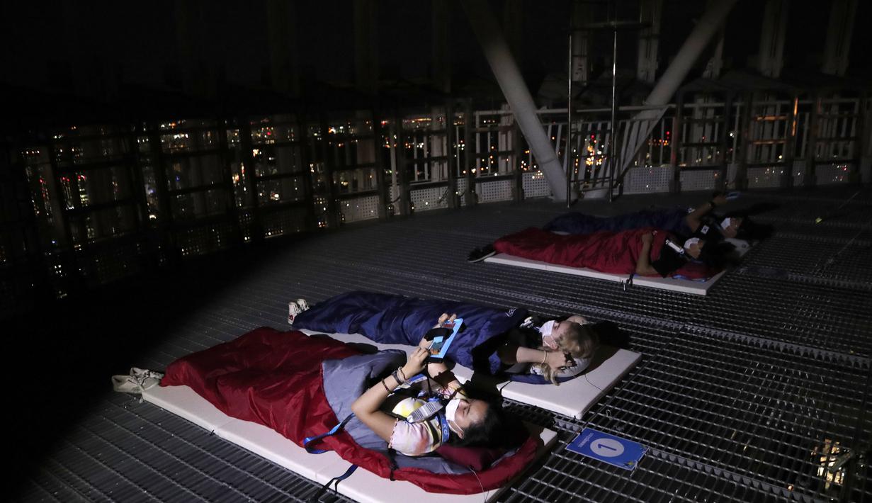 Orang-orang menginap di tempat berkemah semalam di atap gedung pencakar langit di Seoul, Korea Selatan (7/8/2020). Menara Lotte World membuka area berkemah jarak sosial di atap menara dan tanah untuk orang-orang yang jenuh di cuaca musim panas dan Covid-19. (AP Photo/Lee Jin-man)