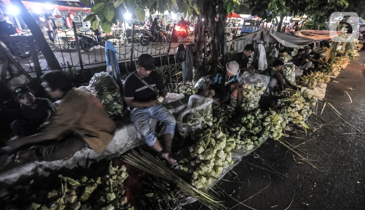 Aktivitas pedagang saat membuat bungkus atau tali ketupat di Pasar Klender, Jakarta Timur, Selasa (11/5/2021) malam. Salah satu pedagang mengaku akibat pandemi corona COVID-19 penjualan ketupat menurun hingga 70 persen. (merdeka.com/Iqbal S Nugroho)