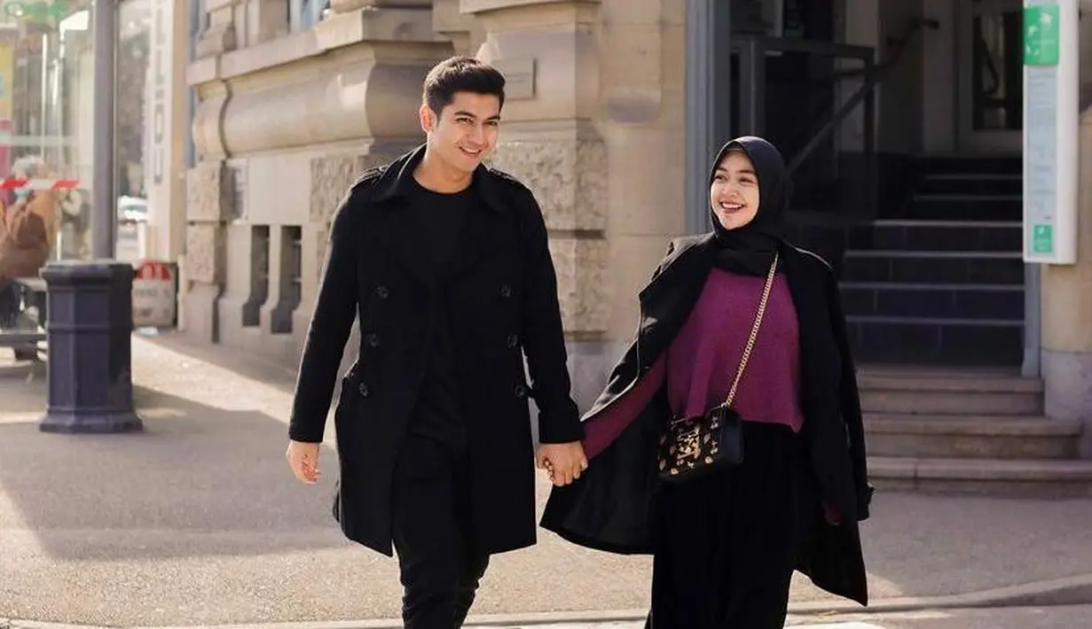 Matching pakai outfit warna hitam, Ria Ricis dan Teuku Ryan terlihat mesra berjalan bergandengan tangan. (Instagram/teukuryantr).