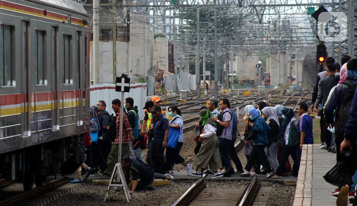 Calon penumpang menyebrang ke peron lain di Stasiun Manggarai, Jakarta, Kamis (13/2/2020). PT KCI melakukan rekayasa perjalanan KRL Bogor dan Bekasi terkait penggantian wesel atau persimpangan rel di stasiun Gambir dan Jakarta Kota. (merdeka.com/Magang/Muhammad Fayyadh)