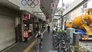 Seorang perempuan mengendarai sepeda di trotoar dengan hiasan Olimpiade di Tokyo, Kamis (15/7/2021). Penyelenggaraan Olimpiade Tokyo akan didadakan di bawah keadaan darurat covid-19 yang diumumkan di Ibu Kota Jepang. (AP Photo/Hiro Komae)