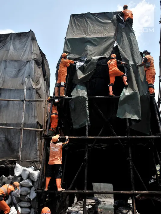 Petugas gabungan membongkar industri pembakaran arang batok di Jalan Inspeksi Cakung Drain, Cilincing, Jakarta, Kamis (19/9/2019). Sebanyak 23 usaha pembakaran arang batok dibongkar menyusul keluhan serta penolakan warga terkait pencemaran udara dan lingkungan. (merdeka.com/Iqbal S Nugroho)