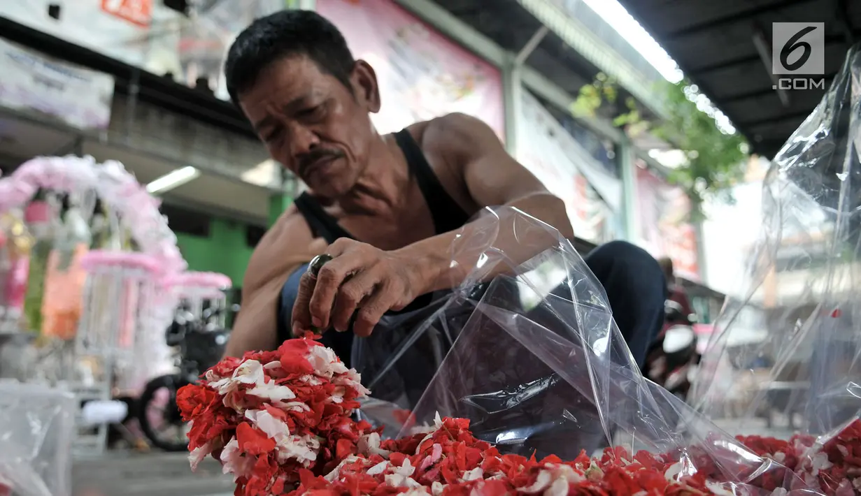 Pedagang memasukkan kembang makam ke dalam plastik saat berjualan di Pasar Rawa Belong, Jakarta, Senin (29/4). Pada hari-hari biasa, pedagang hanya mengantongi Rp 150 ribu per hari. (merdeka.com/Iqbal Nugroho)