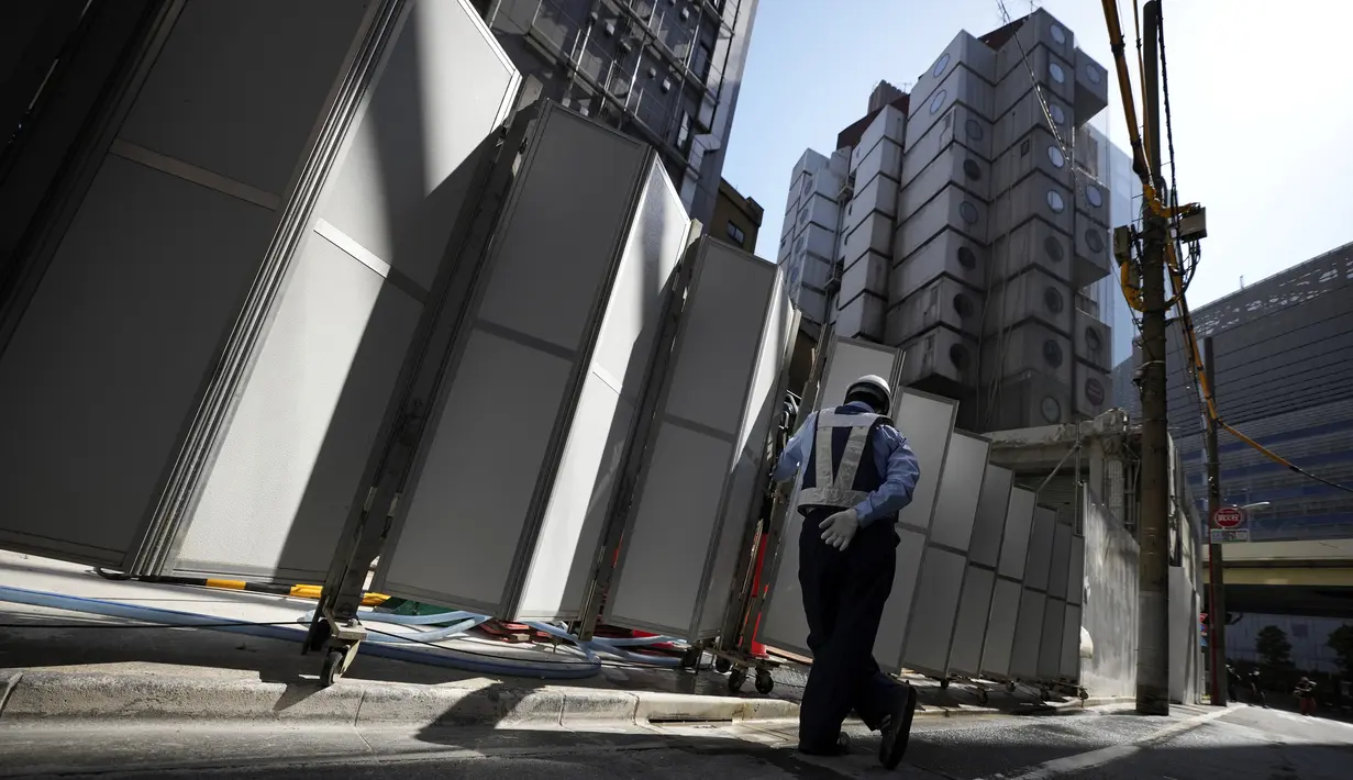 Seorang petugas keamanan mengawasi pembongkaran Nakagin Capsule Tower, bangunan ikonik yang dirancang arsitek Jepang Kisho Kurokawa pada tahun 1972, di distrik Ginza Tokyo, Selasa (12/4/2022). Pekerjaan pembongkaran menara 140 unit kapsul tersebut dimulai Selasa. (AP Photo/Eugene Hoshiko)