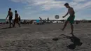 Seorang anak bermain bola di tepi Pantai Prado yang merupakan salah satu garis pantai yang sering dijadikan turis untuk berjemur. (Bola.com/Vitalis Yogi Trisna)