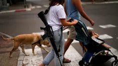 Yehudit, seorang tentara Israel yang sedang tidak bertugas, mendorong troli bersama keponakannya saat mereka berjalan-jalan di pusat Tel Aviv, Israel, Jumat (27/10/2023). (AP Photo/Francisco Seco)