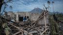 Penduduk desa menyelamatkan barang-barang mereka dari rumahnya yang rusak akibat erupsi Gunung Semeru di desa Curah Kobokan di Lumajang, Jawa Timur, Rabu (8/12/2021). Korban meninggal akibat erupsi Gunung Semeru bertambah menjadi 35 orang hingga Rabu pagi. (Juni Kriswanto / AFP)