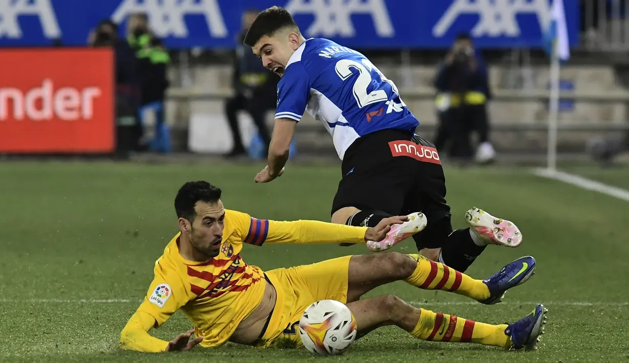 Gelandang Barcelona Sergio Busquets berebut bola dengan bek Deportivo Alaves Martin Aguirregabiria dalam duel pekan ke-22 La Liga 2021/22, di Estadio Mendizorroza, Senin (24/1/2022) dini hari WIB. Gol telat Frenkie De Jong memenangkan Barcelona 1-0. (AP Photo/Alvaro Barrientos)