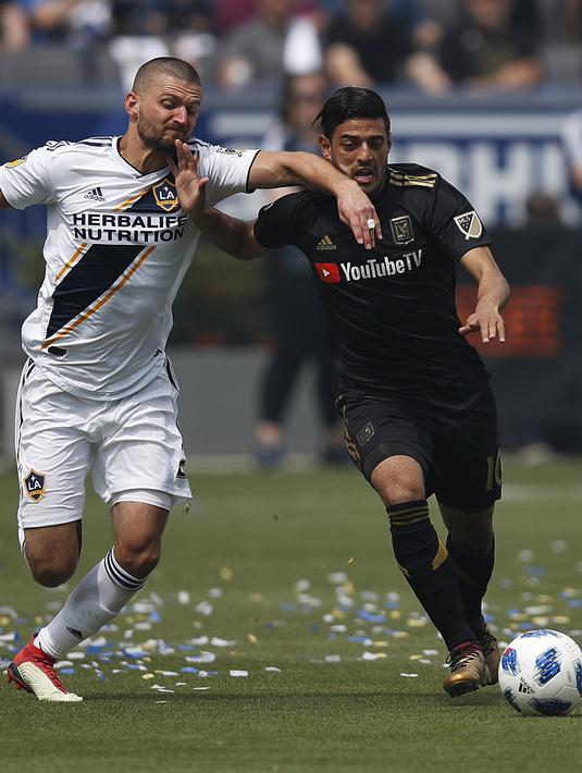 Pemain Los Angeles FC, Carlos Vela (kanan) berebut bola dengan pemain Los Angeles Galaxy, Perry Kitchen pada laga Major League Socccer di StubHub Center,  California, (31/3/2018). LA Galaxy menang 4-3. (AP/Jae C. Hong)