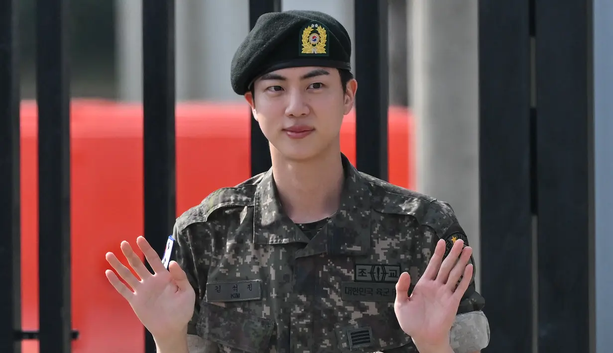 Kim Seok Jin, yang dikenal dengan nama panggung Jin BTS melambai setelah keluar dari dinas wajib militernya di luar pangkalan militer di Yeoncheon, Rabu (12/6/2024). (Jung Yeon-je / AFP)