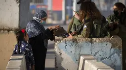 Pasukan Israel menolak mengizinkan seorang perempuan Palestina menyeberangi pos pemeriksaan Qalandia antara kota Ramallah Tepi Barat dan Yerusalem, untuk menghadiri sholat Jumat kedua bulan Ramadhan, karena mereka tidak membawa dokumen vaksinasi COVID-19, Jumat (23/4/2021). (AP Photo/Majdi Mohammed)