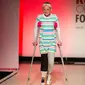 Model difabel dibantu dengan kruk berjalan mengenakan koleksi The Runway of Dreams selama peragaan busana di New York, Rabu (5/8). Pagelaran itu menampilkan kaum difabel menggunakan pakaian yang disesuaikan dengan kondisi mereka. (AP/Kevin Hagen)