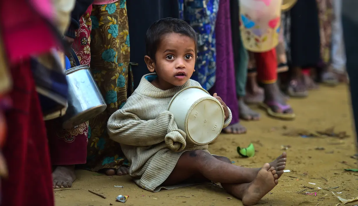 Seorang anak pengungsi muslim Rohingya menunggu bantuan makanan di kamp pengungsi Thankhali di Distrik Ukhia, Bangladesh, (12/1). Etnis Rohingya lari dari Myanmar setelah tentara memulai kampanye pemerkosaan dan pembunuhan. (Munir UZ ZAMAN/AFP)