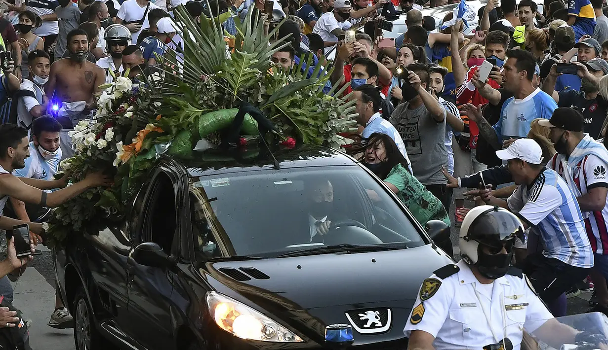 Penggemar berkerumun di samping mobil jenazah legenda sepak bola Argentina, Diego Armando Maradona, dalam perjalanan dari istana kepresidenan Casa Rosada ke pemakaman, Kamis (26/11/2020) waktu setempat. Diego Maradona meninggal karena serangan jantung pada usia 60 tahun. (AFP/Raul Fferrari/ TELAM)