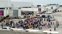 Penumpang dievakuasi di landasan pesawat saat penembakan di Bandara Fort Lauderdale, Florida, AS (6/1). Peristiwa penembakan terjadi di tempat pengambilan bagasi bandara di Terminal 2. (AP Photo/Wilfredo Lee)