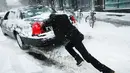 Seorang pria mendorong mobilnya saat badai salju melanda kawasan Brooklyn, New York City, AS (9/2). Ribuan sekolah negeri di New York dan Boston diliburkan untuk mengantisipasi datangnya badai salju. (Spencer Platt / Getty Images / AFP)